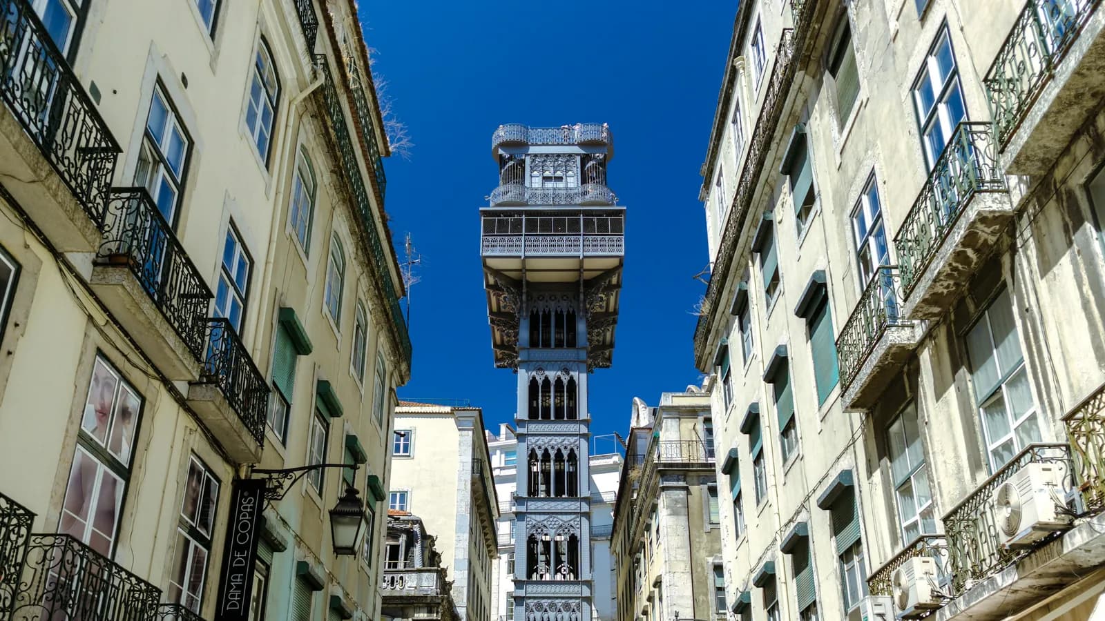 Elevador de Santa Justa zwischen Altbauten in der Baixa von Lissabon vor blauem Himmel
