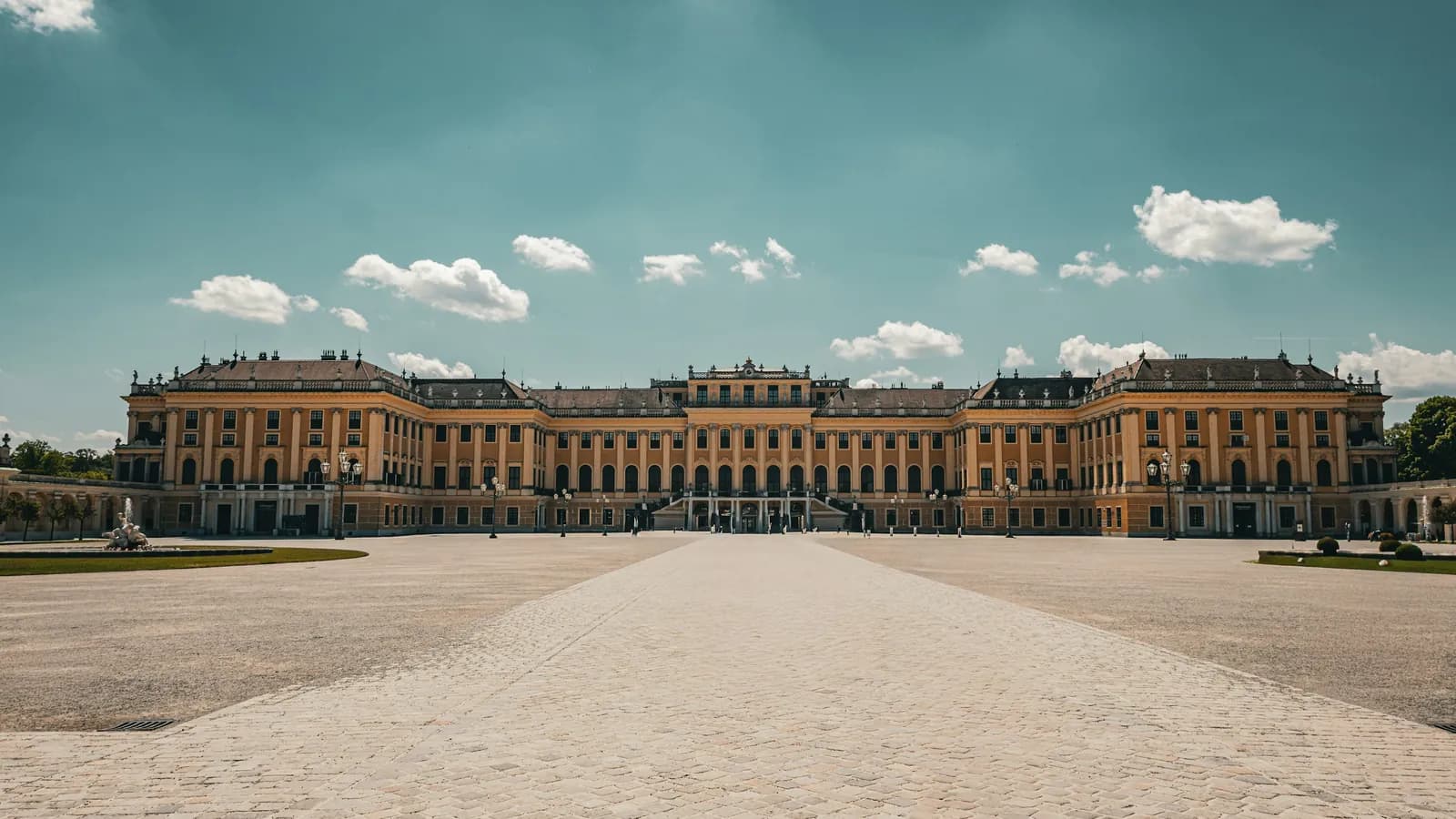Schloss Schönbrunn in Wien mit weitem Ehrenhof unter blauem Himmel
