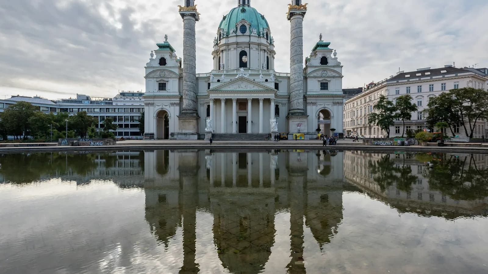 Karlskirche in Wien mit Kuppel und Säulen, die sich im Wasserbecken spiegelt